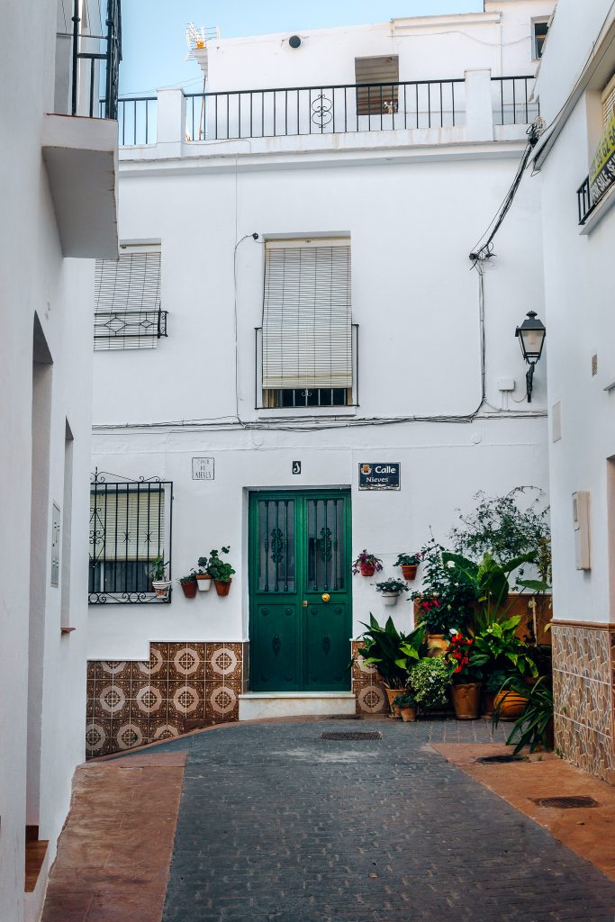 Green doors, white house decorated with flowers in Torrox Pueblo, Spain